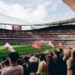Täysi Emirates Stadium Valioliigaottelun alla. Arsenal-kannattajat täyttävät katsomot ja kentän laidalla liehuu seuran lippuja.