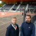 Joel Häkämies ja Vesa Karjalahti poseeraavat pesäpallostadionin katsomon edessä.