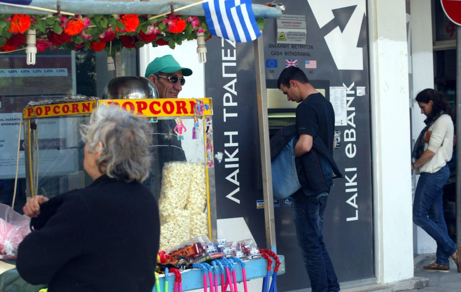 Mies pankkiautomaatilla. Etualalla katukoju.