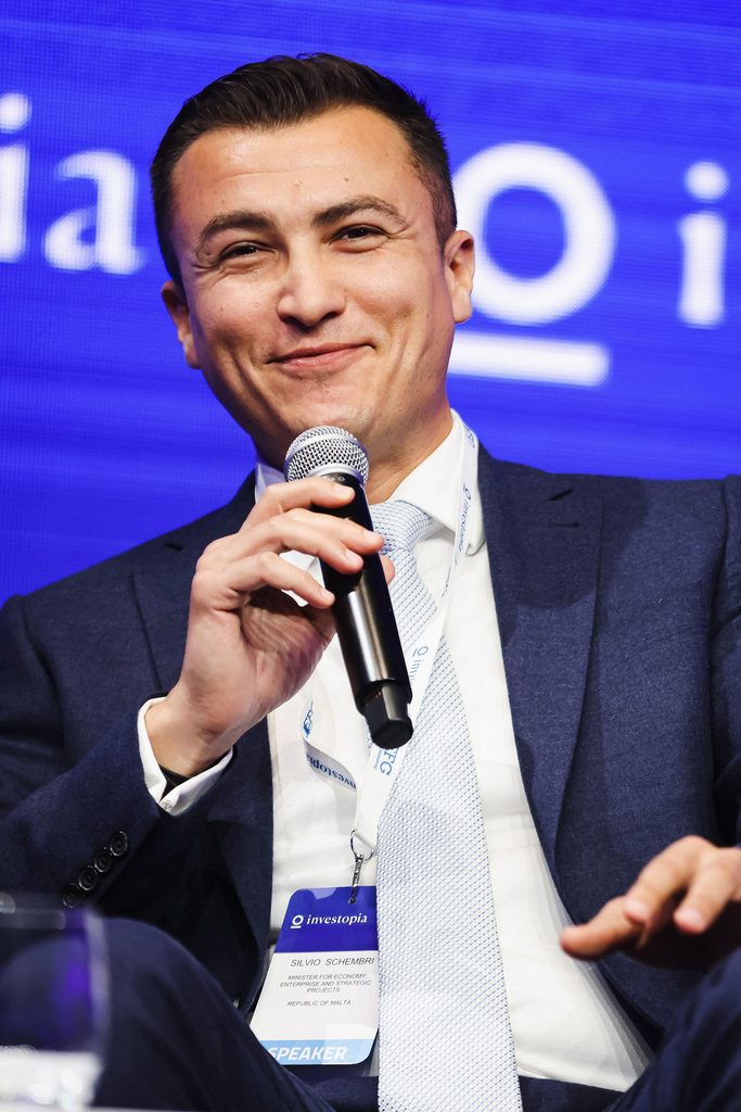 Silvio Schembri hymyilee lavalla mikrophoni kädessään.