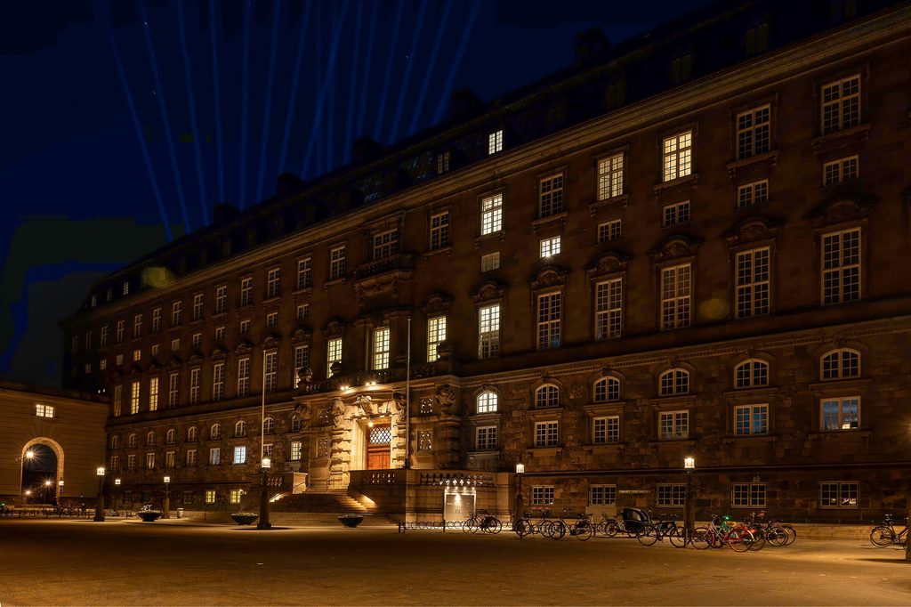 Christianborgin palatsi Kööpenhaminan valofestivaalin aikaan iltahämärssä. Yläpuolella näkyy laaservaloja.