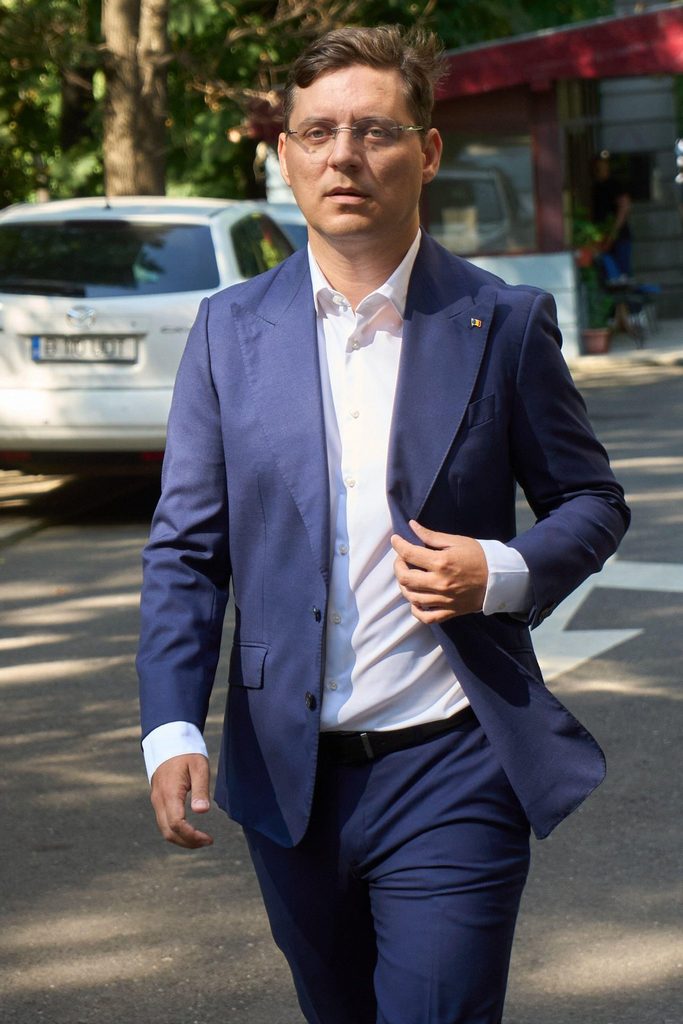 Victor Negrescu kävelee Bucharestissa päällää puku ja romanian lippupinssi.